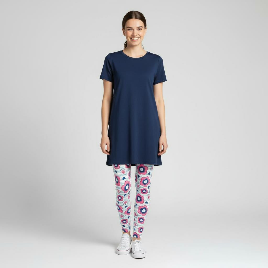 Woman wearing a navy blue tunic and daisy patterned leggings on a white background