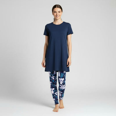 Woman wearing a navy blue tunic and koala patterned leggings on a light grey background