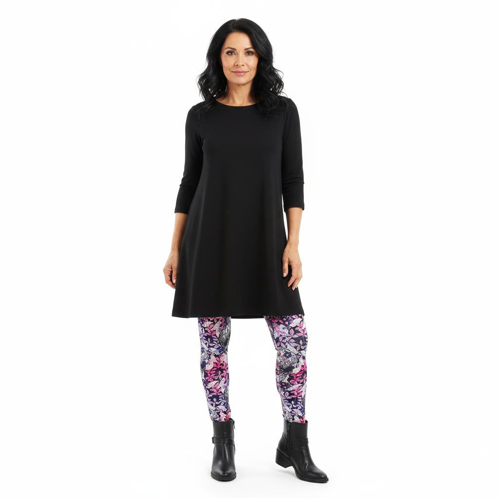 Woman wearing a black dress and colorful leggings on a white background