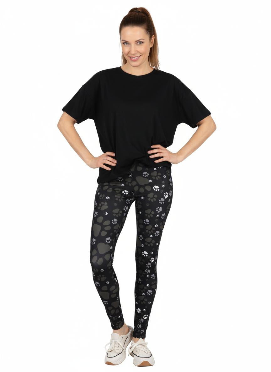 Woman wearing black t-shirt and paw print patterned leggings on a white background
