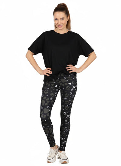 Woman wearing black t-shirt and paw print patterned leggings on a white background